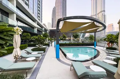 a pool with chaise lounge chairs and a large umbrella at Livbnb-Modern 2BR with Partial Burj Khalifa View in Dubai