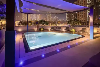 a swimming pool on top of a building at night at Livbnb-Modern 2BR with Partial Burj Khalifa View in Dubai