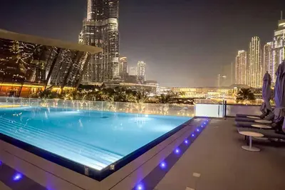a swimming pool on top of a building at night at Livbnb-Modern 2BR with Partial Burj Khalifa View in Dubai