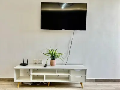 a tv on a white wall with a plant on it at Homes2Retreat - Serene 1BR Getaway with Stunning Views in Dubai