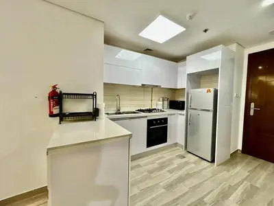 a kitchen with white cabinets and a refrigerator at Homes2Retreat - Serene 1BR Getaway with Stunning Views in Dubai