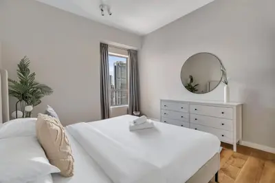 a white bedroom with a large bed and a mirror at GuestReady - Chic High-Rise with Canal Views in Dubai