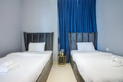two beds in a room with blue curtains at Elegant 4 bedrooms plus maid Villa in the Heart of Dubai Hills in Dubai