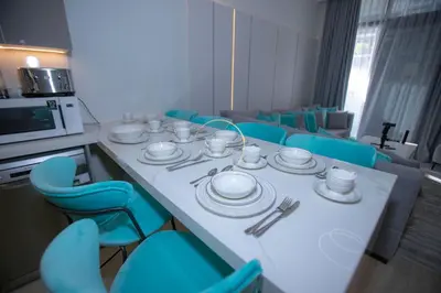 a room with a table with blue chairs and plates at 3BHK Apartment located in Azizi riviera 34 in Dubai