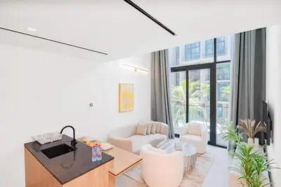 a living room with a couch and a table at Escape24 Cozy Studio with Pool View in JVC in Dubai