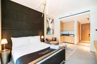 a bedroom with a large bed and a living room at Escape24 Cozy Studio with Pool View in JVC in Dubai