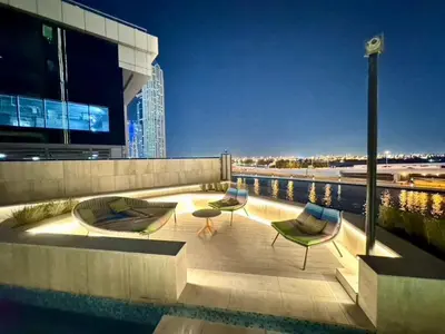 a patio with two chairs and a pool on a building at Mahogany 6 - 2BR 8PAX - Infinity Pool & High-floor in Dubai