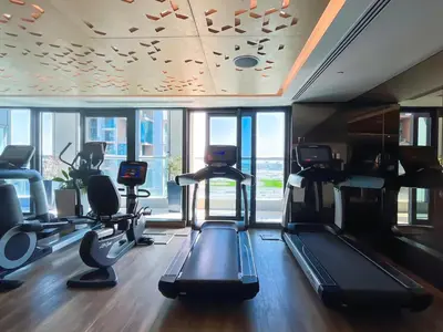 a gym with treadmills and ellipticals in a room with windows at 2BR Apartment in Paramount Tower in Dubai