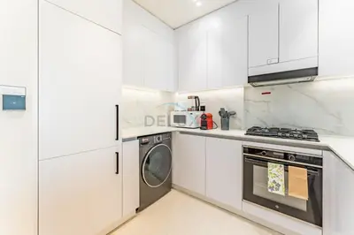 a kitchen with white cabinets and a washer and dryer at Skyline and Community Views 1BR with Private Balcony Near Community Park, Binghatti Amber, Jumeirah Village Circle by Deluxe Holiday Homes in Dubai