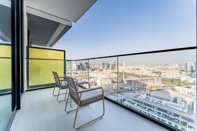 a balcony with two chairs and a table and glass windows at Skyline and Community Views 1BR with Private Balcony Near Community Park, Binghatti Amber, Jumeirah Village Circle by Deluxe Holiday Homes in Dubai