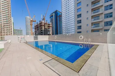 a swimming pool in a city with tall buildings at Modern Compact Studio in JVC in Dubai