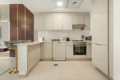 an empty kitchen with white cabinets and appliances at Modern Compact Studio in JVC in Dubai