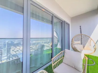 a wicker chair sitting on a balcony with an ocean view at Elegant 2-BR with modern comfort in Dubai