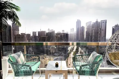 a balcony with chairs and a table and a view of a city at Chic City Retreat Steps from Dubai Mall & Dubai Opera in Dubai