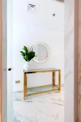 a gold console table with a mirror and a plant at Chic City Retreat Steps from Dubai Mall & Dubai Opera in Dubai