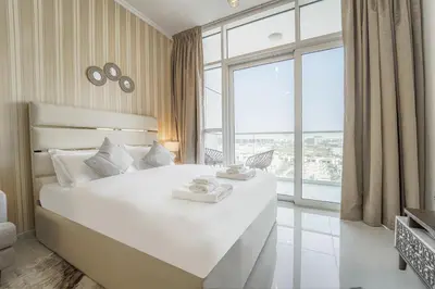 a bedroom with a large white bed with a large window at Studio in Damac H1 by Deleguest in Dubai