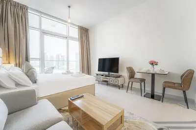 a white living room with a couch and a tv at Studio in Damac H1 by Deleguest in Dubai