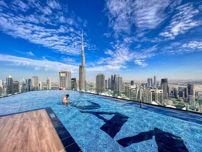 a man in a infinity pool on the top of a skyscraper at Stunning 1BR High Floor with Rooftop Infinity Pool in Dubai