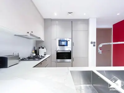 a white kitchen with a stove and a refrigerator at Chic Comfort at oxford Residence in Dubai