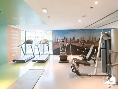 a gym with cardio machines and a mural of a city at Chic Comfort at oxford Residence in Dubai
