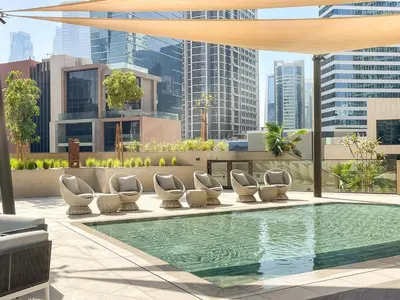 a pool with chaise lounge chairs on the roof of a building at Luxe 2BR Retreat, Canal Views & Prime Dubai Stay Near Attractions in Dubai