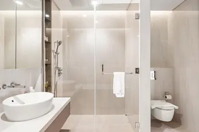 a white bathroom with a sink and a shower at Luxe 2BR Retreat, Canal Views & Prime Dubai Stay Near Attractions in Dubai