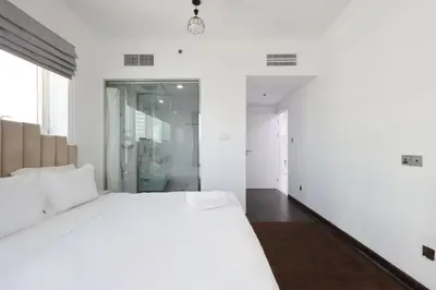 a white bedroom with a large bed and a bathroom at Livbnb-Upgraded 3B with Marina View,Near Promenade in Dubai