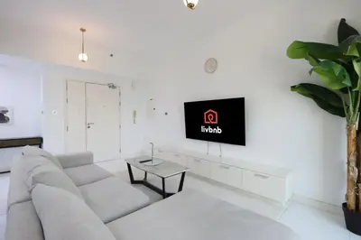 a living room with a couch and a tv on a wall at Livbnb-Upgraded 3B with Marina View,Near Promenade in Dubai