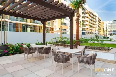 a patio with tables and chairs under a pergola at Chic Modern Studio in Azizi Riviera in Dubai