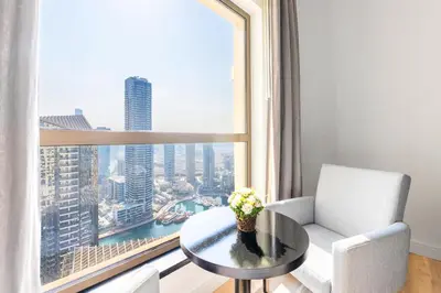 a living room with a table and a large window at Luxe Marina View Retreat! 2BDRM in Dubai