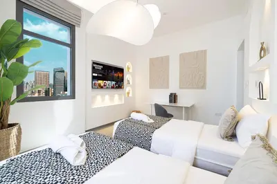 two beds in a room with a window at Black & Bold - Aesthetic Stay in Dubai