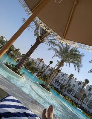 a person laying on a hammock looking out at a resort with palm trees at Stylish Urban-Jungle-Studio in Al Barari, Dubai in Dubai