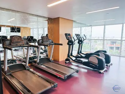a gym with several tread machines in a room at Luxurious Studio in Damac Hills in Dubai