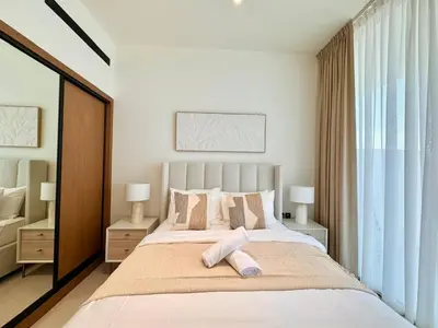 a bedroom with a large bed and a large window at Chic Jvc 1br Pool Access, Balcony & Parking in Dubai