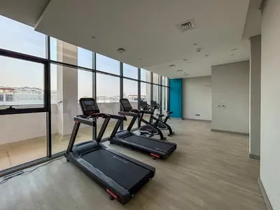 a gym with three treadmills in a room with windows at Frank Porter - Azizi Riviera 16 in Dubai