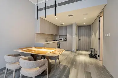 a kitchen with a wooden table and chairs at Elegant 1BDR apartment in JVC in Dubai