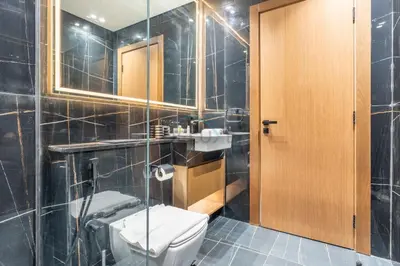 a bathroom with a toilet and a sink and a mirror at High-Rise 1BR with Lake and City Views Easy Access to Downtown and Marina, Binghatti Onyx, Jumeirah Village Circle by Deluxe Holiday Homes in Dubai