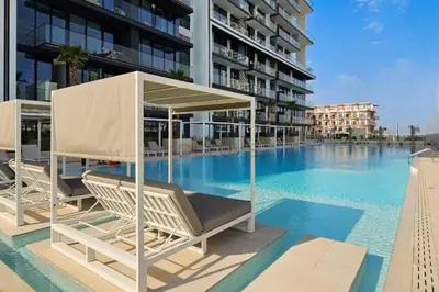 a swimming pool with two lounge chairs and a building at High-Rise 1BR with Lake and City Views Easy Access to Downtown and Marina, Binghatti Onyx, Jumeirah Village Circle by Deluxe Holiday Homes in Dubai