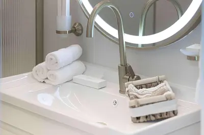 a bathroom with a sink with towels and a mirror at 1BR Beach House Vibes in Prime Marina Location in Dubai