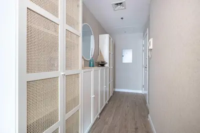 a hallway with a white wall with a mirror at 1BR Beach House Vibes in Prime Marina Location in Dubai