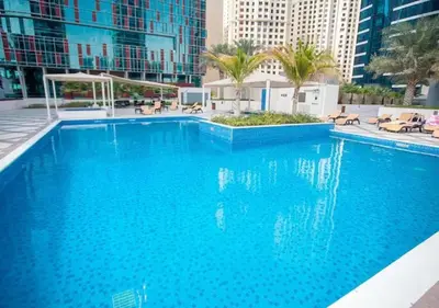a large blue swimming pool with palm trees and buildings at 1 BD in Bay Central with the Iconic Marina Views in Dubai