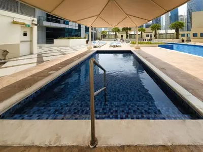 a swimming pool with an umbrella in a building at 1 BD in Bay Central with the Iconic Marina Views in Dubai