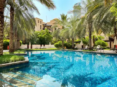 a swimming pool with palm trees in a resort at Luxury 1BR in Zaafran With Stunning Burj Khalifa View in Dubai