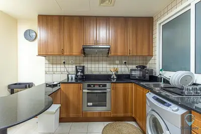 a kitchen with wooden cabinets and a washer and dryer at 1 BR Blue Chic Dubai Marina, Steps to Beach! in Dubai