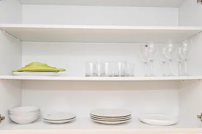a kitchen with white dishes and glasses on a shelf at Exquisite studio - Highest at the Palm Tower in Dubai