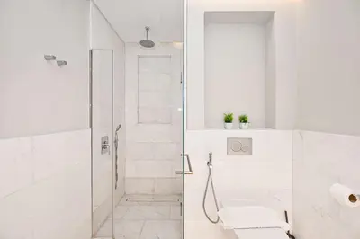 a white bathroom with a shower and a toilet at Exquisite studio - Highest at the Palm Tower in Dubai