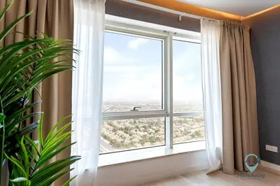 a large window in a room with a plant at Bright Modern 1BR Heart Of JLT Skyline Views in Dubai