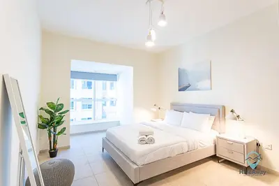 a white bedroom with a bed and a window at 1BR Charming Modern 5Min to Beach Dubai Marina in Dubai