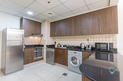 a kitchen with stainless steel appliances and wooden cabinets at 1BR Charming Modern 5Min to Beach Dubai Marina in Dubai