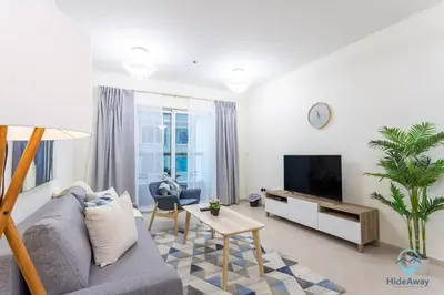a living room with a couch and a tv at 1BR Charming Modern 5Min to Beach Dubai Marina in Dubai